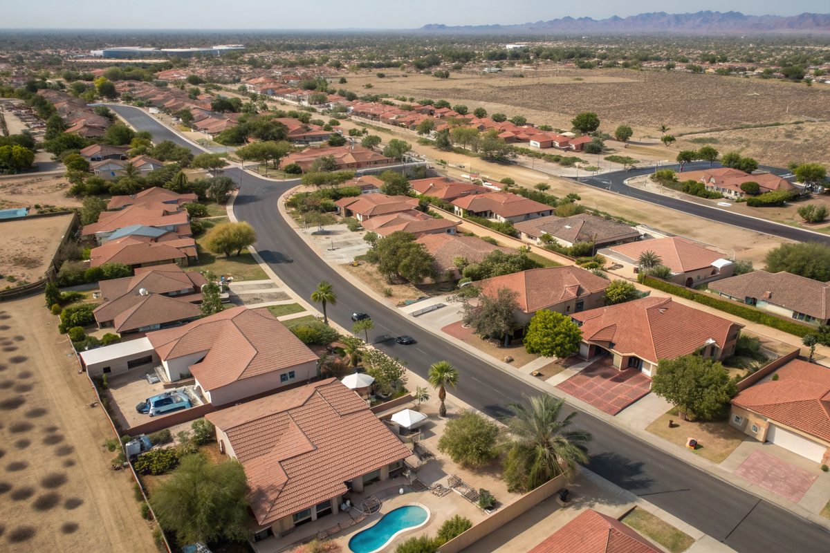 Aerial view of a desert neighborhood of tile and shingle roofs with pools and palm trees